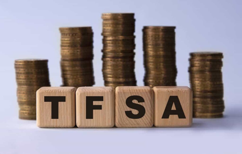 3 of the Best Canadian Stocks to Buy and Hold in a TFSA TFSA (Tax free savings account) acronym on wooden cubes on the background of stacks of coins